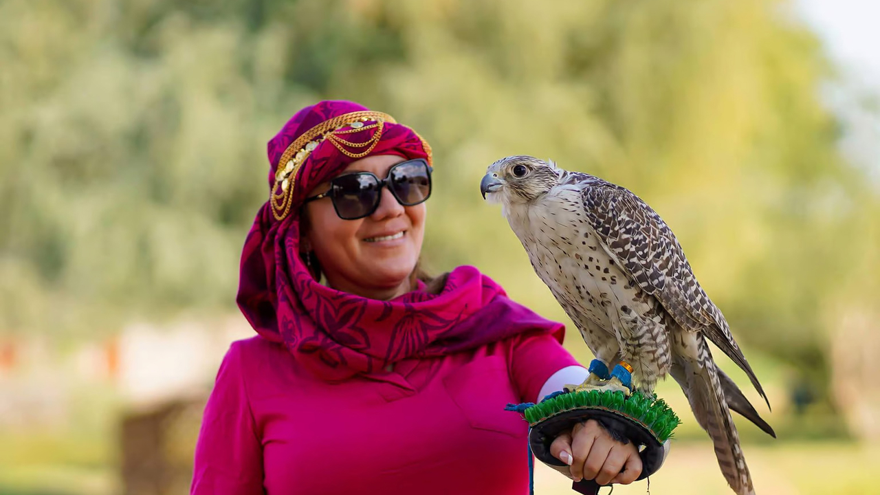 A smiling guest holding a falcon on a gloved arm