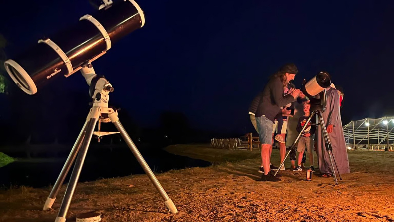 Guests looking through a telescope in the desert at night